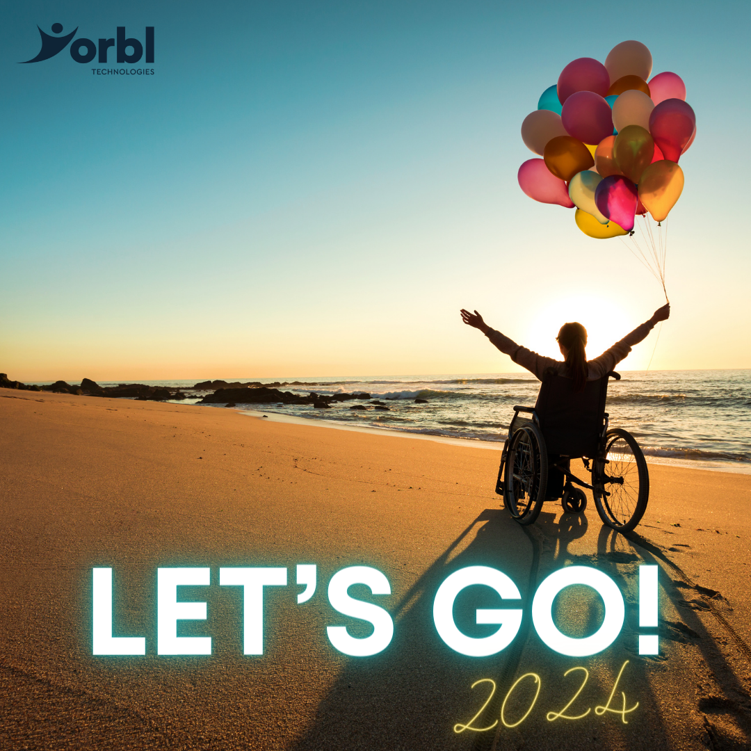 A person in a wheelchair sat on a beach at sunset holding a collection of balloons and holding arms in the air.