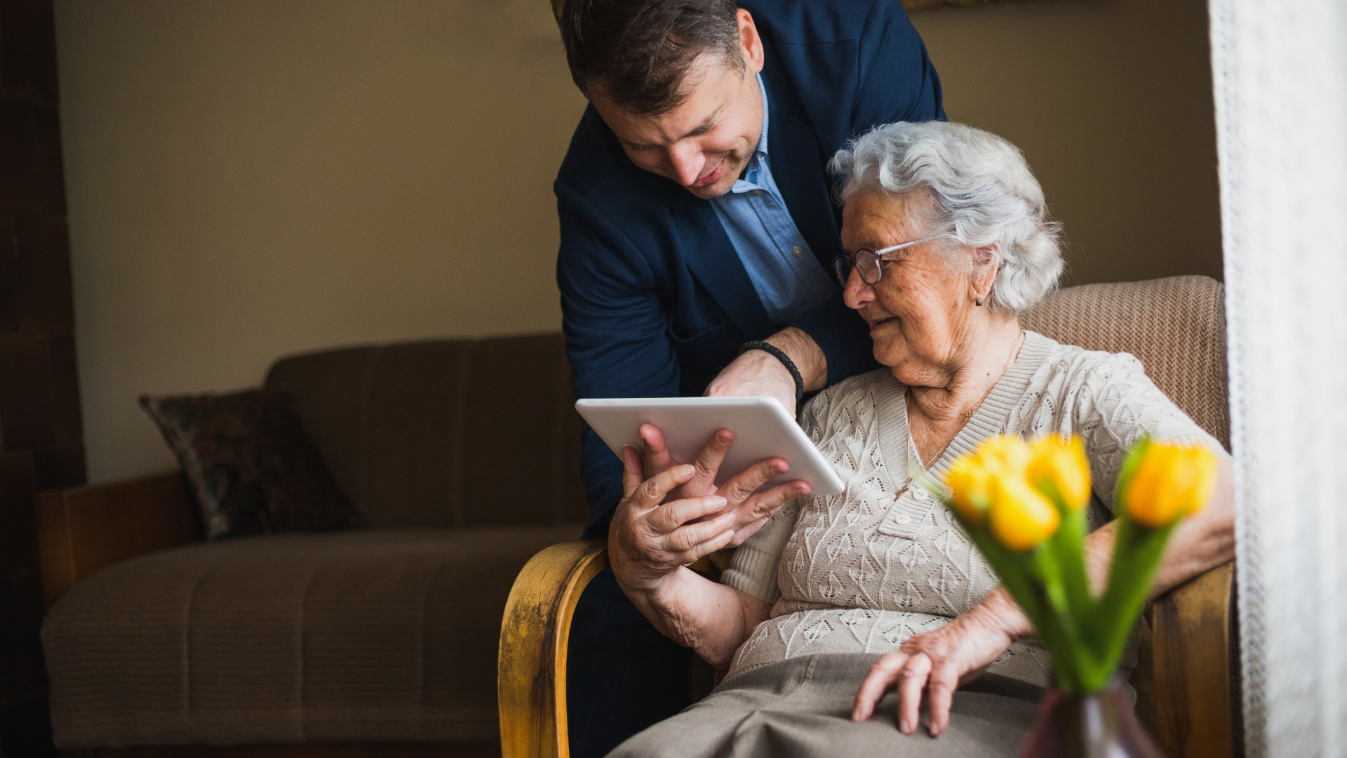 A family member showing a senior lady how to use a tablet